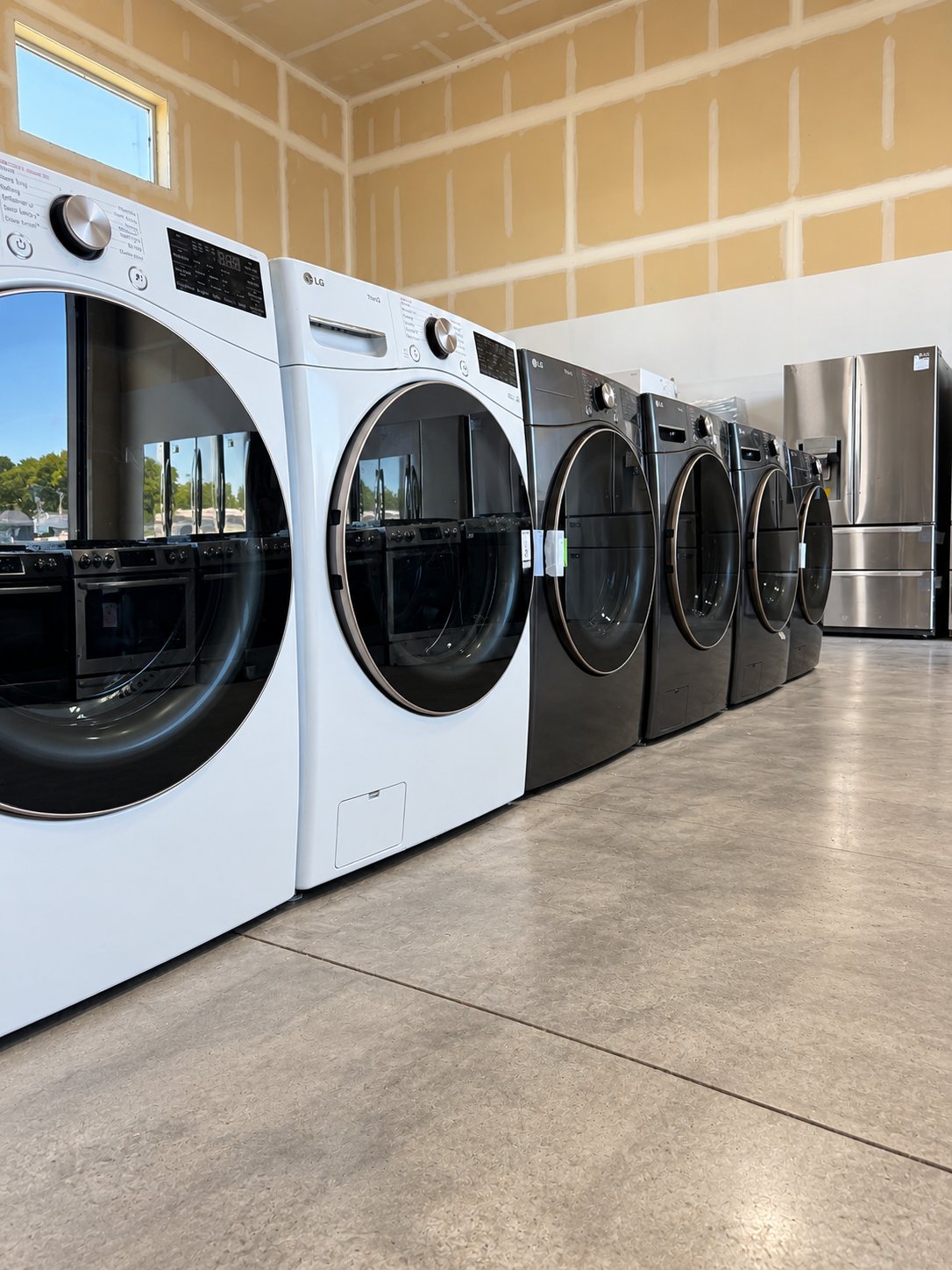 Row of commercial dryers and black ovens in modern laundromat showroom