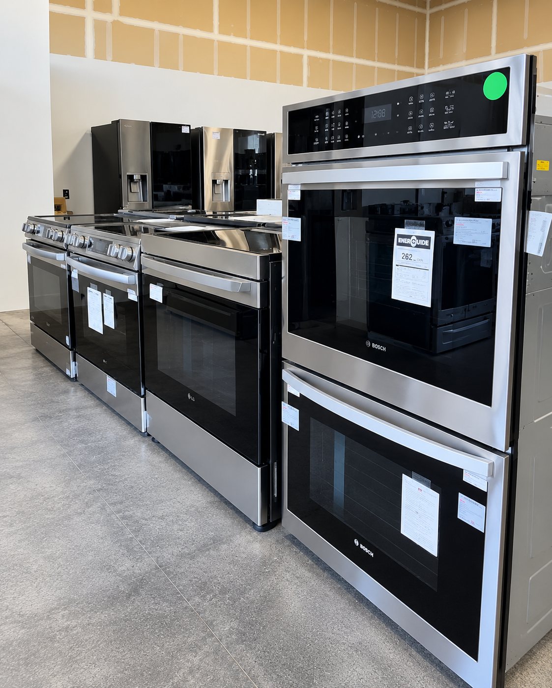 Display of stainless steel kitchen appliances including ovens and refrigerators in showroom