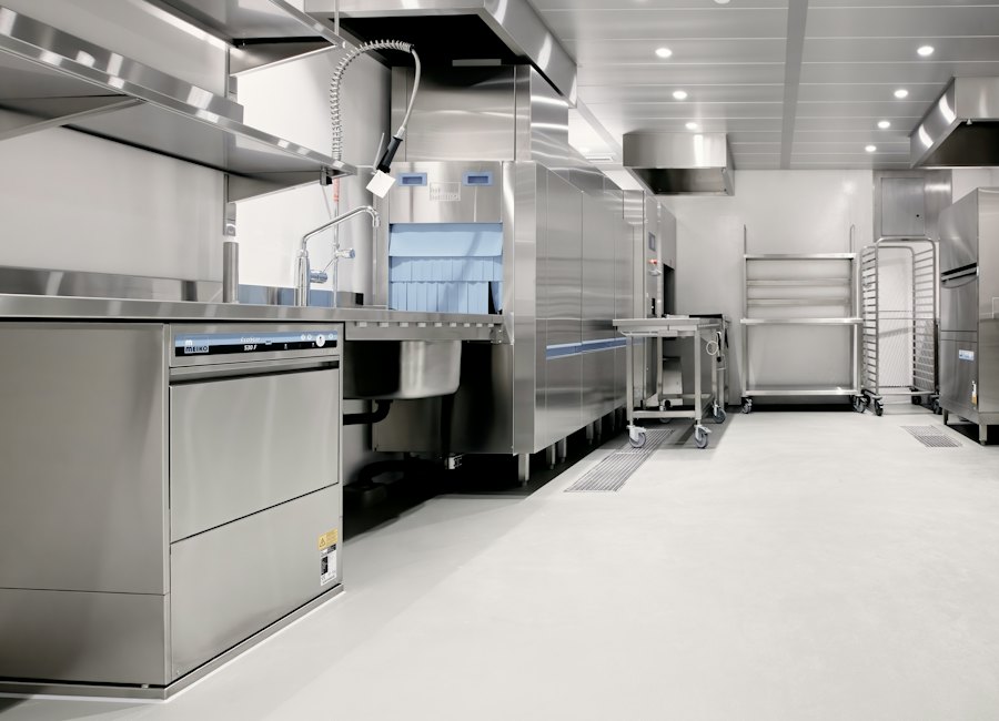 Modern commercial kitchen with stainless steel equipment, dishwasher, and prep stations