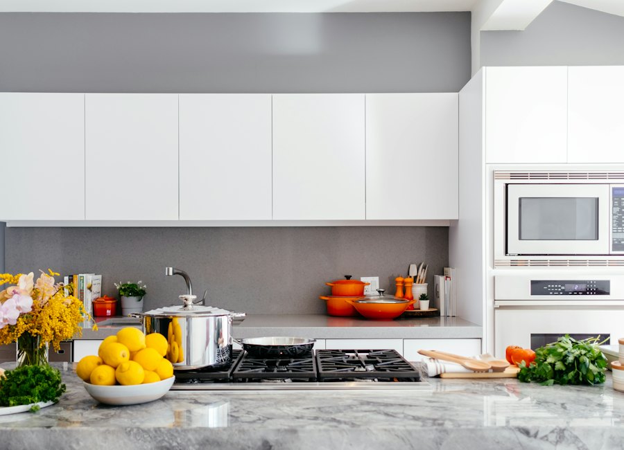 Modern white kitchen with marble countertop, gas range, and bright yellow lemons in white bowl
